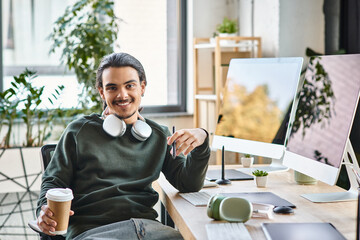 Relaxed young man with stylus pen and coffee smiling at a startup post-production workspace - 746551605