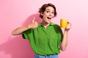 Photo portrait of attractive young woman hold coffee mug show thumb up dressed stylish green...