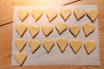 A formed cookies in the form of a heart on a baking sheet on a wooden table in the kitchen. Cooking desserts at home. Top view