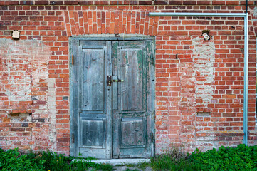Old wooden door in front of a red brick wall
