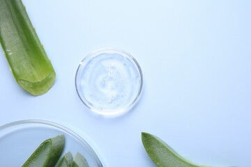Aloe vera leaves and cosmetic gel on light blue background, top view. Space for text