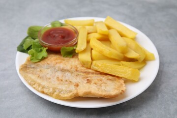 Delicious fish and chips with ketchup and lettuce on gray table, closeup