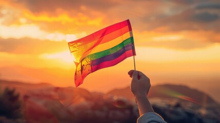 hand waves a colorful gay pride LGBT rainbow flag at sunset on a natural landscape in summer - obrazy, fototapety, plakaty