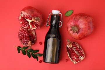 Tasty pomegranate sauce in bottle and fruits on red background, flat lay