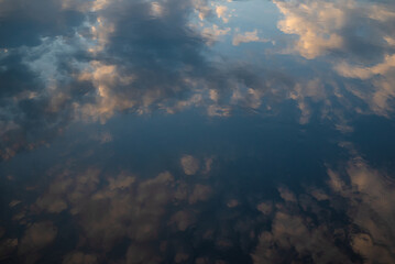 Sunset sky reflected in water. Pink clouds and blue sky reflection in still lake - 746563253