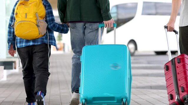 Mother, father and their sons walking with suitcases to the airport. Concept of the vacation and tourism.