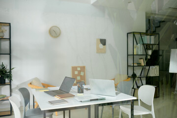 Big table with laptops and planners on it in meeting room in office of startup company