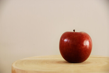 On the wooden surface lies a juicy, red apple, like a captivating ruby, tempting with its...