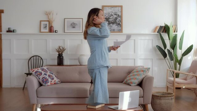 young woman walks around the room and rehearses the character lines holding script in hands. makes mistake and gets angry and irritated