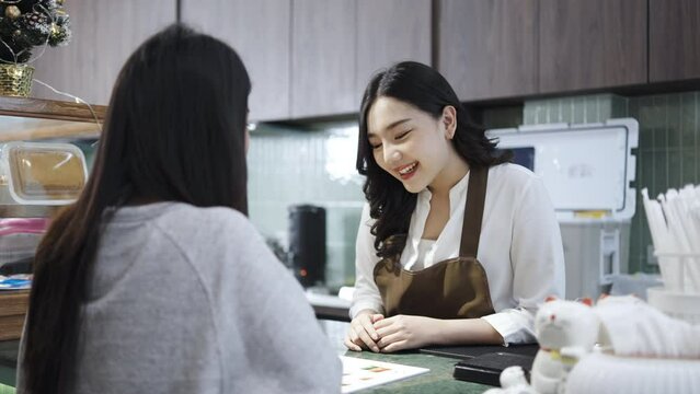 Young asian beautiful female customer select coffee or juice items. with a young woman barista working at the cafe or restaurants counter, entrepreneurial concept Starting a small business, lifestyle