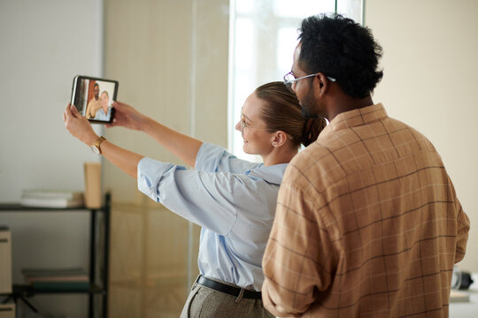 Coworkers taking selfie on tablet for company blog