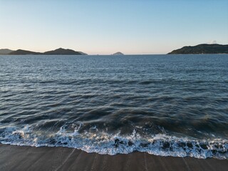 雲ひとつない夕暮れの海岸に打ち寄せる波
