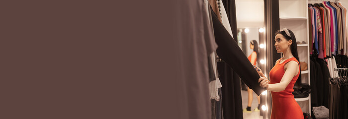 Naklejka premium Real young woman shopping in a clothing store. Reflections of a buyer in the mirror