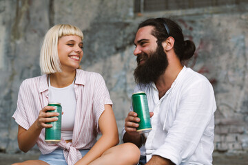 Closeup of young couple is drinking beer in cans in an urban environment