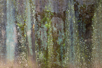 Concrete wall with moss and streaks of water in different shades of green, blue and gray