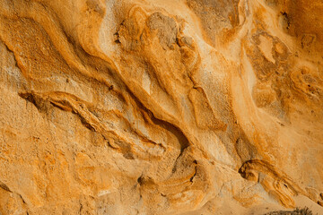 Natural texture background of sandstone rocks with lines, curves, prints in the As Amoeiras and Formosa beach cliffs in Santa Cruz, Portugal.