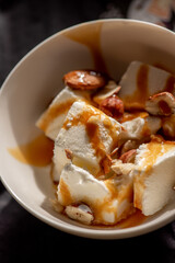 slices of ice cream with caramel syrup and almonds in a plate. homemade dessert.