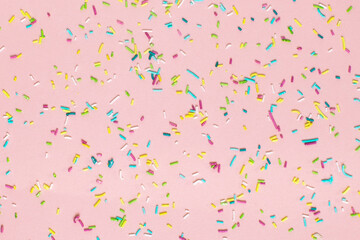 Trendy pattern of colorful sprinkles on pink background. Concept for decoration cake and bakery. 