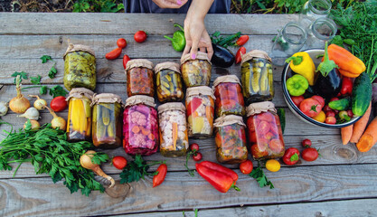 Woman canning vegetables in jars on the background of nature. preparations for the winter