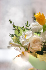 a delicate spring bouquet in yellow and white with tulips, roses and irises. a greeting card with a spring bouquet.