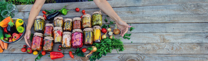 Woman canning vegetables in jars on the background of nature. preparations for the winter