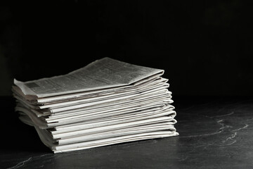 Stack of newspapers on dark stone table. Journalist's work - obrazy, fototapety, plakaty