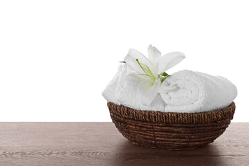 Obraz na płótnie Canvas Fresh towels and lily flower on wooden table against white background. Space for text