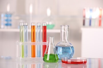 Laboratory analysis. Different glassware with liquids on white table against blurred background....