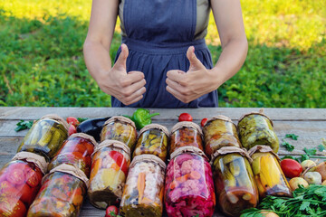 Woman canning vegetables in jars on the background of nature. preparations for the winter