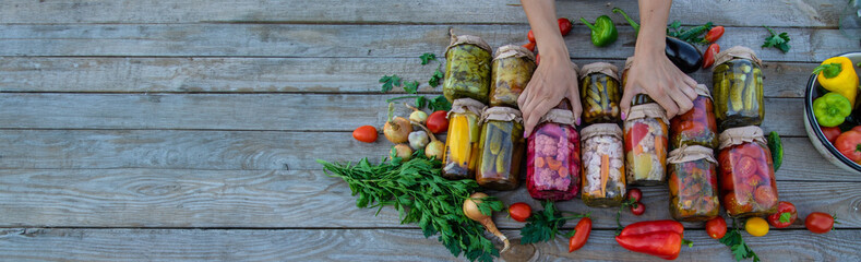Woman canning vegetables in jars on the background of nature. preparations for the winter