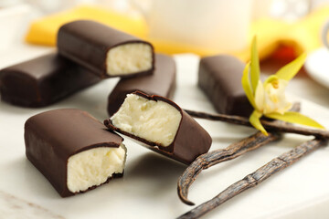 Glazed curd cheese bars, vanilla pods and flower on white board, closeup