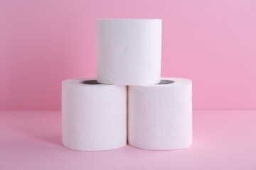 Soft toilet paper rolls on pink background, closeup