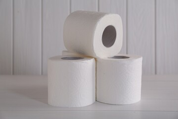 Many soft toilet paper rolls on white wooden table
