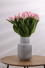 Beautiful bouquet of fresh pink tulips on table against light background