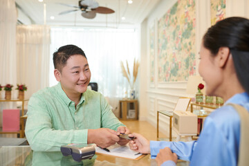 Polite wax salon receptionist accepting payment from client