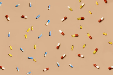 Variety of different pills capsules arranged on peach background. Assortment includes various colors, shapes, and sizes of medication, highlighting diversity of treatments available