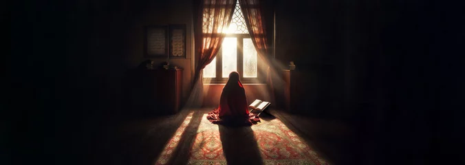 Foto op Plexiglas A Muslim woman, covered in a red veil, kneels in prayer as the sun's rays filter through a nearby window. © LADALIDI