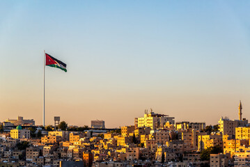 Beautiful sunset cityscape of Amman, Jordan with Jordanian flag flying in the wind