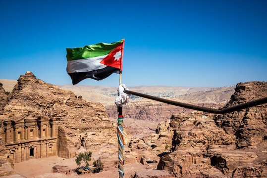 Jordanian flag blowing in the wind with the building known as the Monastery in the background in Petra, Jordan
