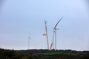 Wind turbine being repaired, assisted by crane and elevator