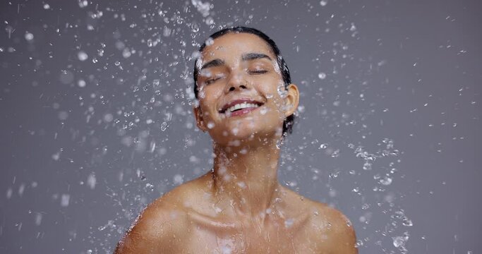 Water, beauty and face of woman on gray background for cleaning, spa wellness and cosmetics. Dermatology, skincare and person with splash for washing, facial treatment and healthy skin in studio