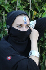 Portrait of a woman with green eyes wearing arabic eastern veil on her head and indian jewelry	
