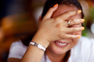 Fototapeta premium Playful shy woman hiding face with her hand. .