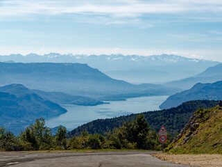 View from Grand Colombier peak towards Bourget lake and alps, asphalt road with speed limit sign...