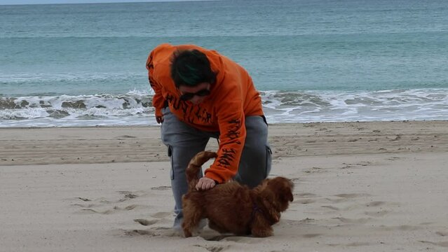 Mujer joven jugando con la perrita Nami en la arena de la Playa de San Juan, Alicante, Espa&ntilde;a