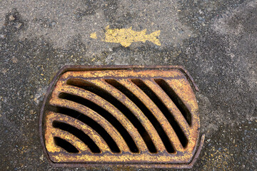 A  street grate drain with an old stencil of a fish on the pavement above it.