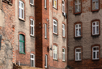 Windows in a red brick building, old building with falling plaster.