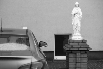A statue of Christ next to an expensive car, a synthesis of the Catholic Church in Poland.