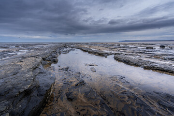 Exposed rocks and pools on Granville Beach Redcar at low tide. The photograph is looking out to sea on a very overcast day.