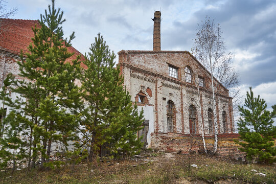 Abandoned destroyed brick building with high chimney. Old facility industrial premises, Glass Factory area overgrown with trees, Krasnoyarsk, Memory 13 Bortsov. 